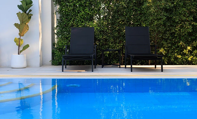 A serene poolside scene featuring a lounge chair beside a potted plant, inviting relaxation and leisure.