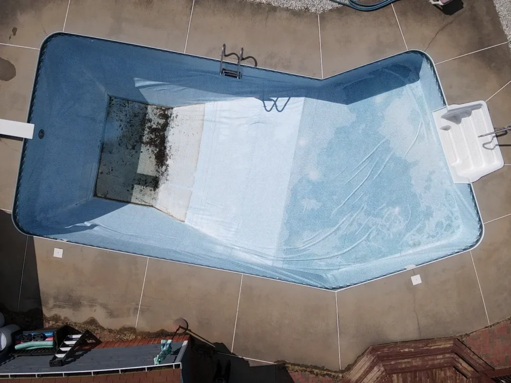 Empty pool photographed from above with visible dirt at the bottom