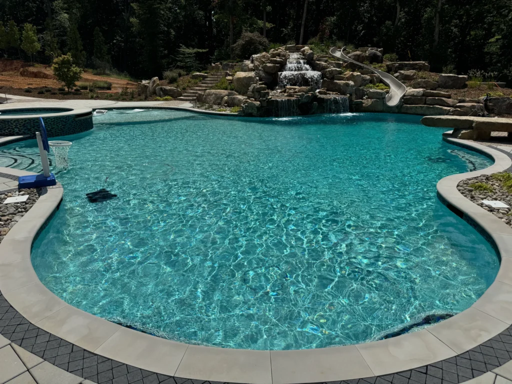Resort-style swimming pool with rock waterfall feature and built-in water slide