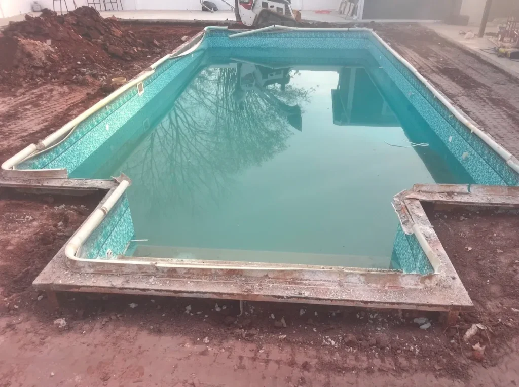 Rectangular swimming pool under construction with exposed concrete and dirt surroundings
