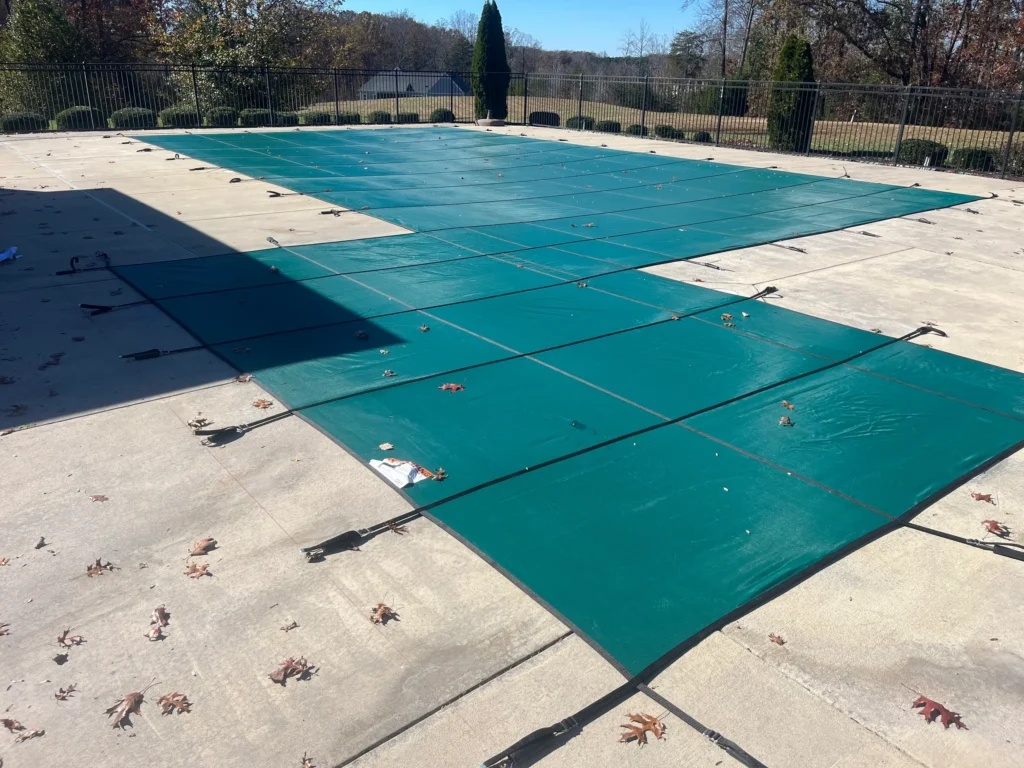 Large swimming pool covered with a green safety cover for winter protection