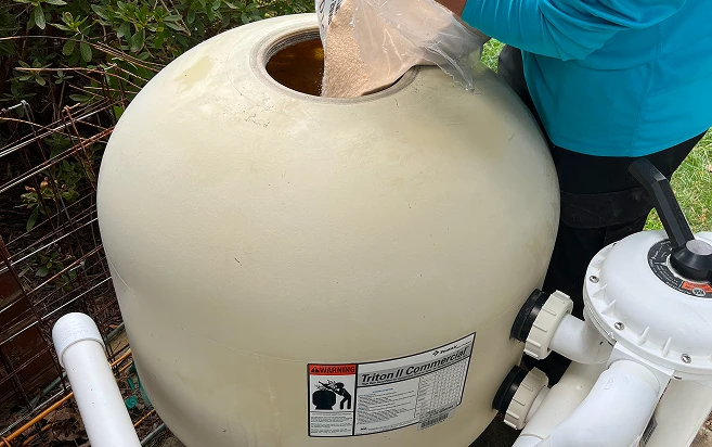A woman places a plastic bag over a large white tank, preparing it for storage or protection.