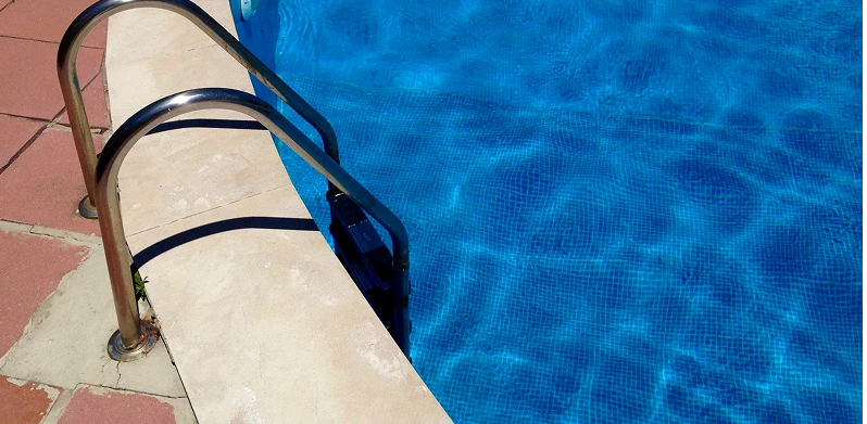 A swimming pool with a ladder under a clear blue sky, inviting for a refreshing swim on a sunny day.