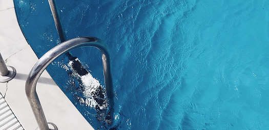 1. A man swims in a clear blue pool, creating ripples in the water around him.